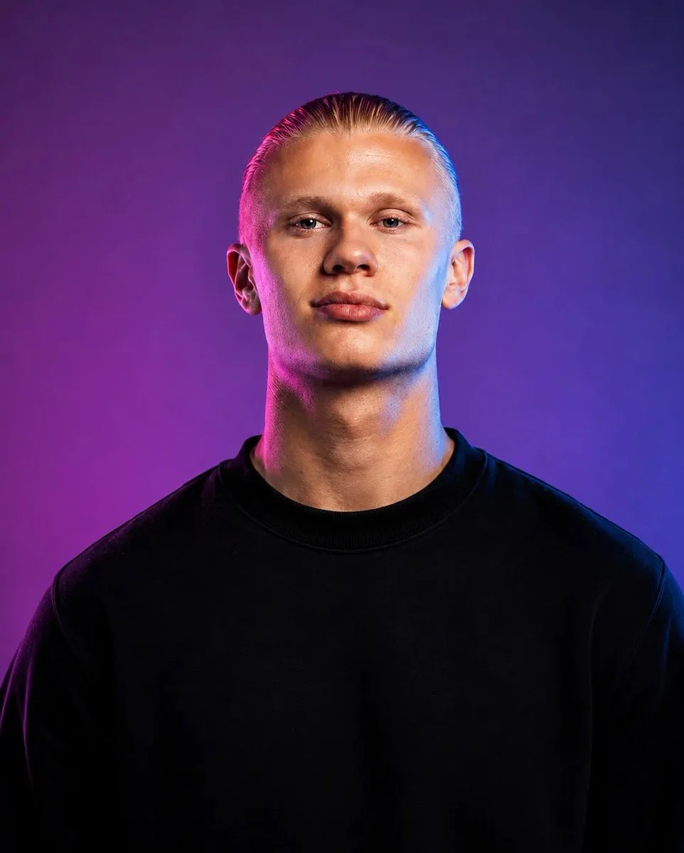 A confident man in black tee under magenta and blue studio lights