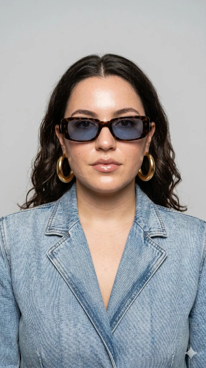 A confident model in retro sunglasses poses for editorial fashion portrait
