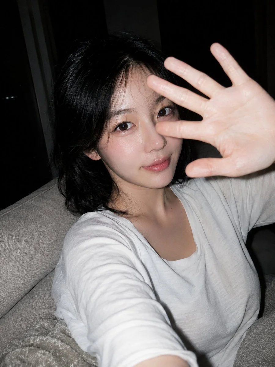A gentle hand blocks the flash while she smiles in dim room