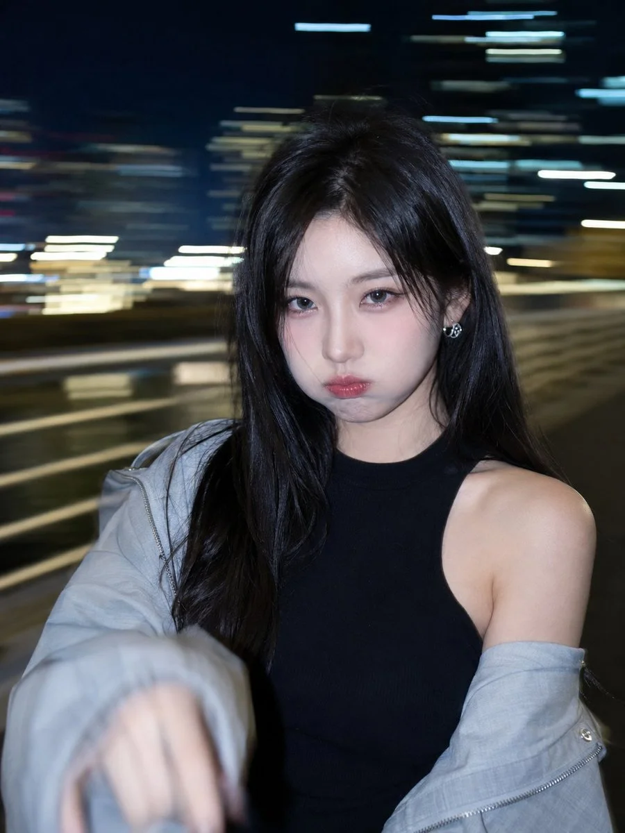 A Korean woman pouts by a neon bridge in slow-shutter night photography