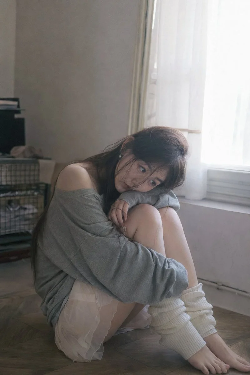 A melancholic Chinese girl rests by a sunlit window