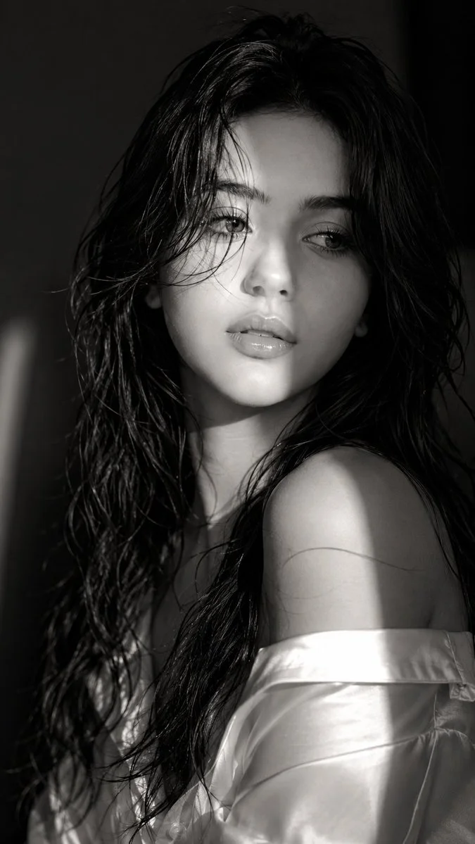 A mysterious woman in monochrome light glances away with glossy lips.