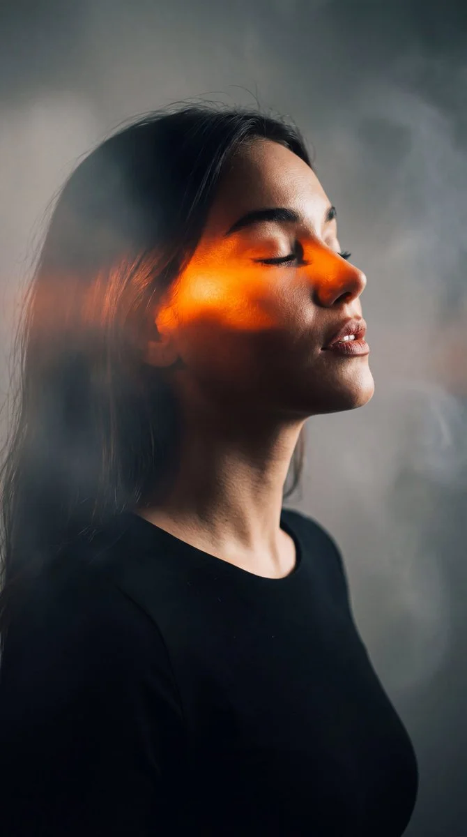 A serene side profile woman glows in orange chiaroscuro light