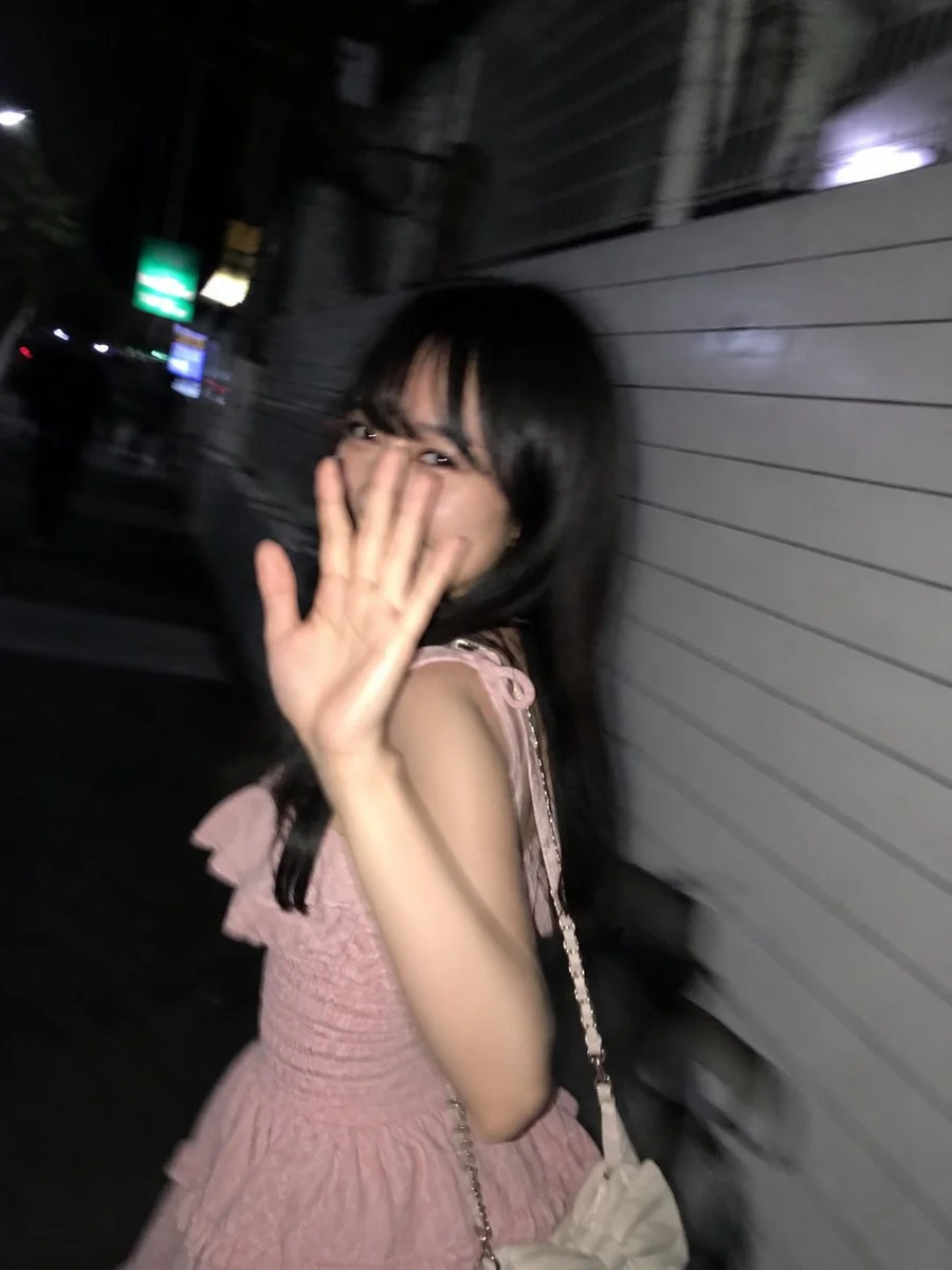 A shy woman turns back mid-walk under streaked Tokyo lights