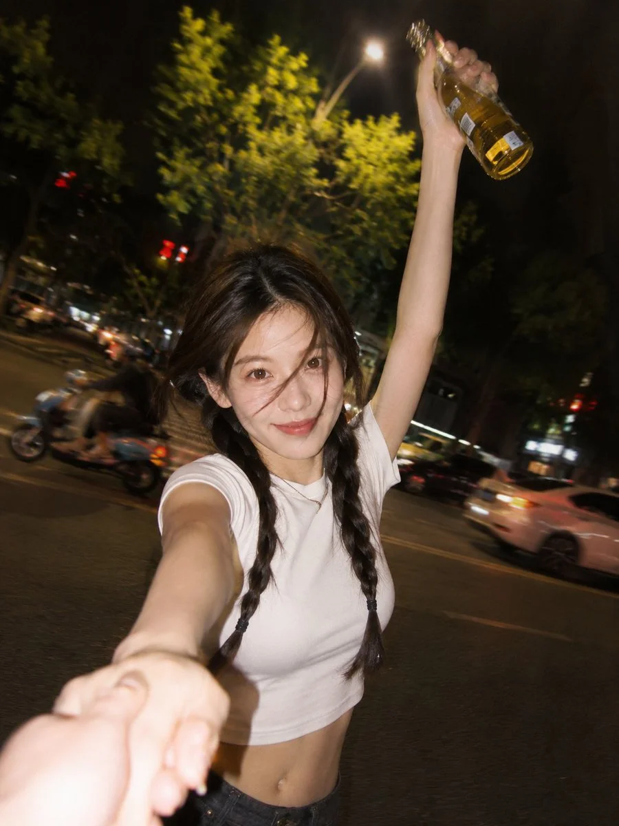 A smiling woman holds a golden drink in a night street