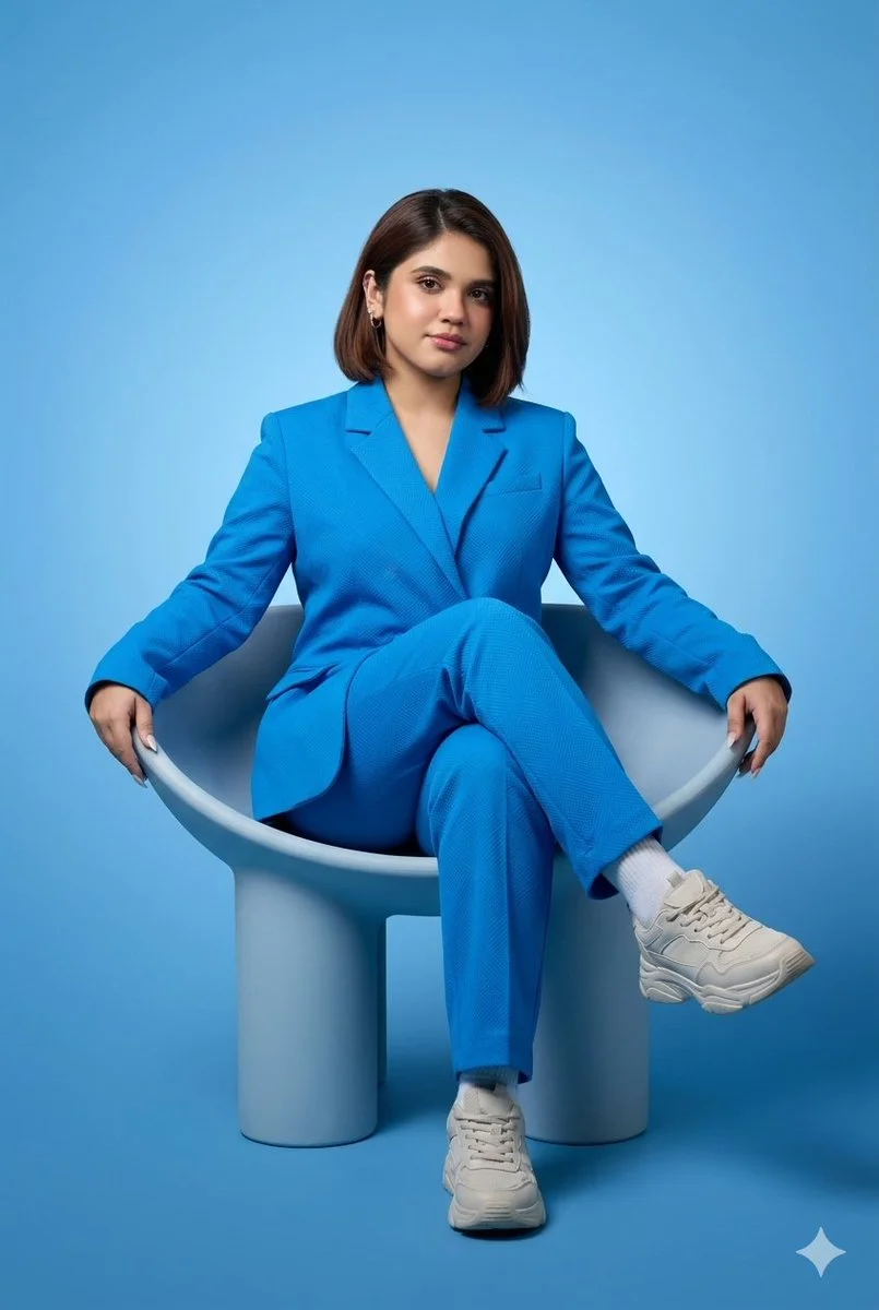 A woman in a blue suit and sneakers sits in a modern chair.