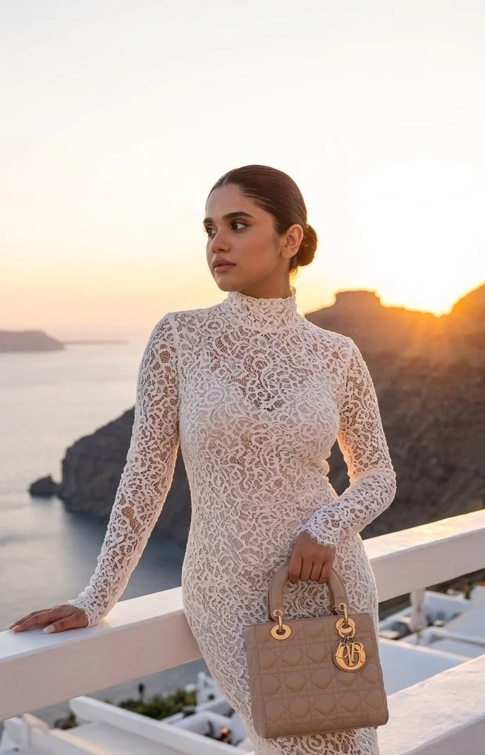 A woman in a white dress poses on a terrace at sunset