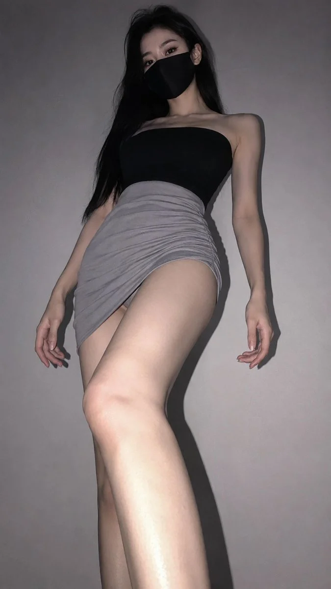 A woman in black mask gazes downward from low angle