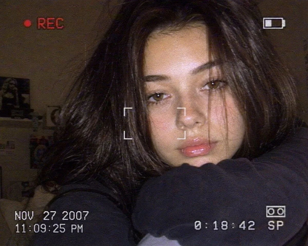 A woman rests her face on sweater arms in warm dim light