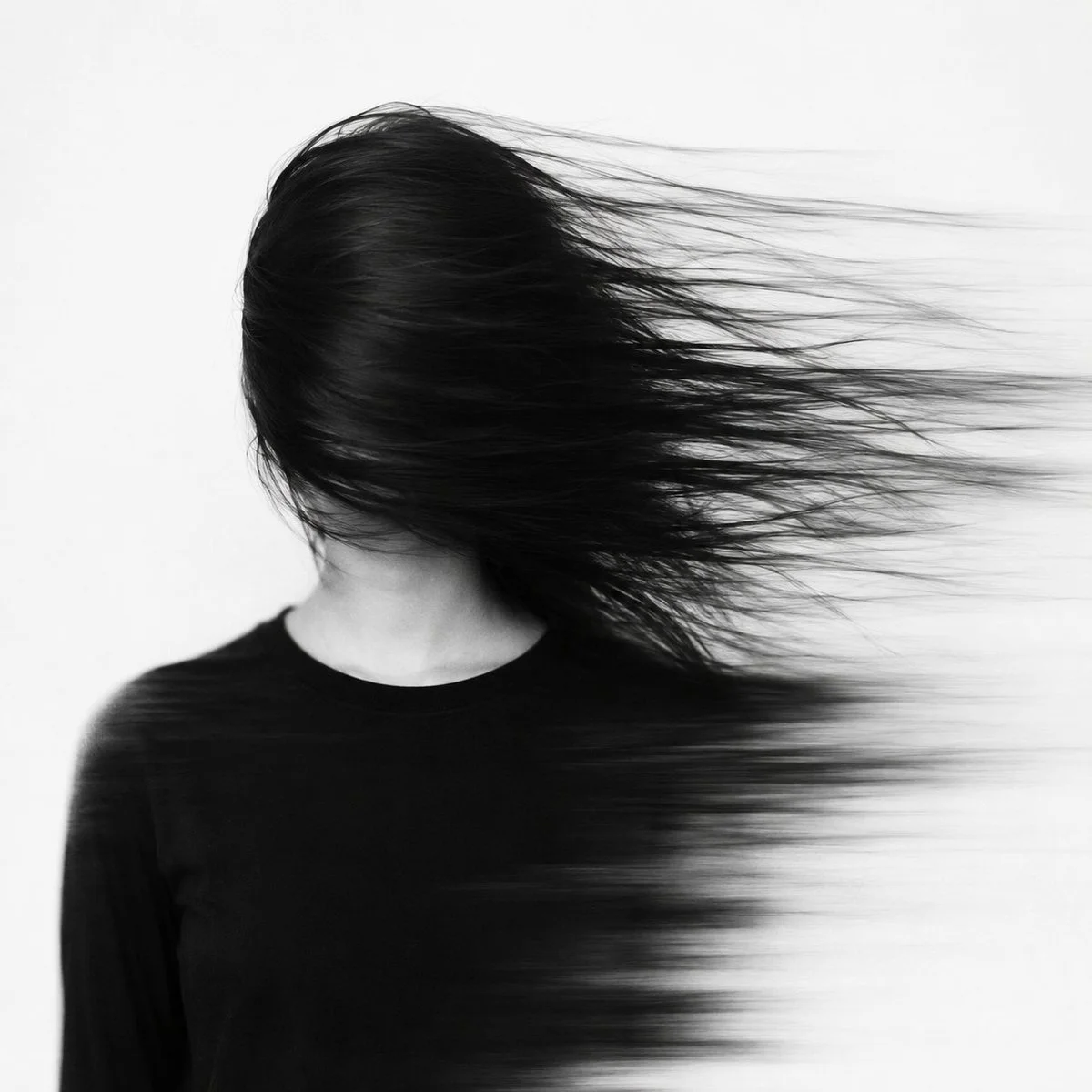 A woman's face dissolves into sweeping black hair strands