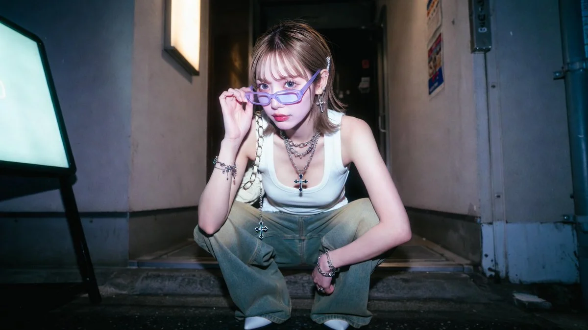 A woman squats at a Kabukicho bar entrance pulling down her glasses