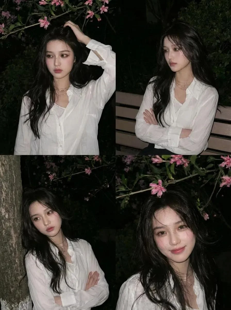 A young Asian woman stands beneath pink blossoms at night