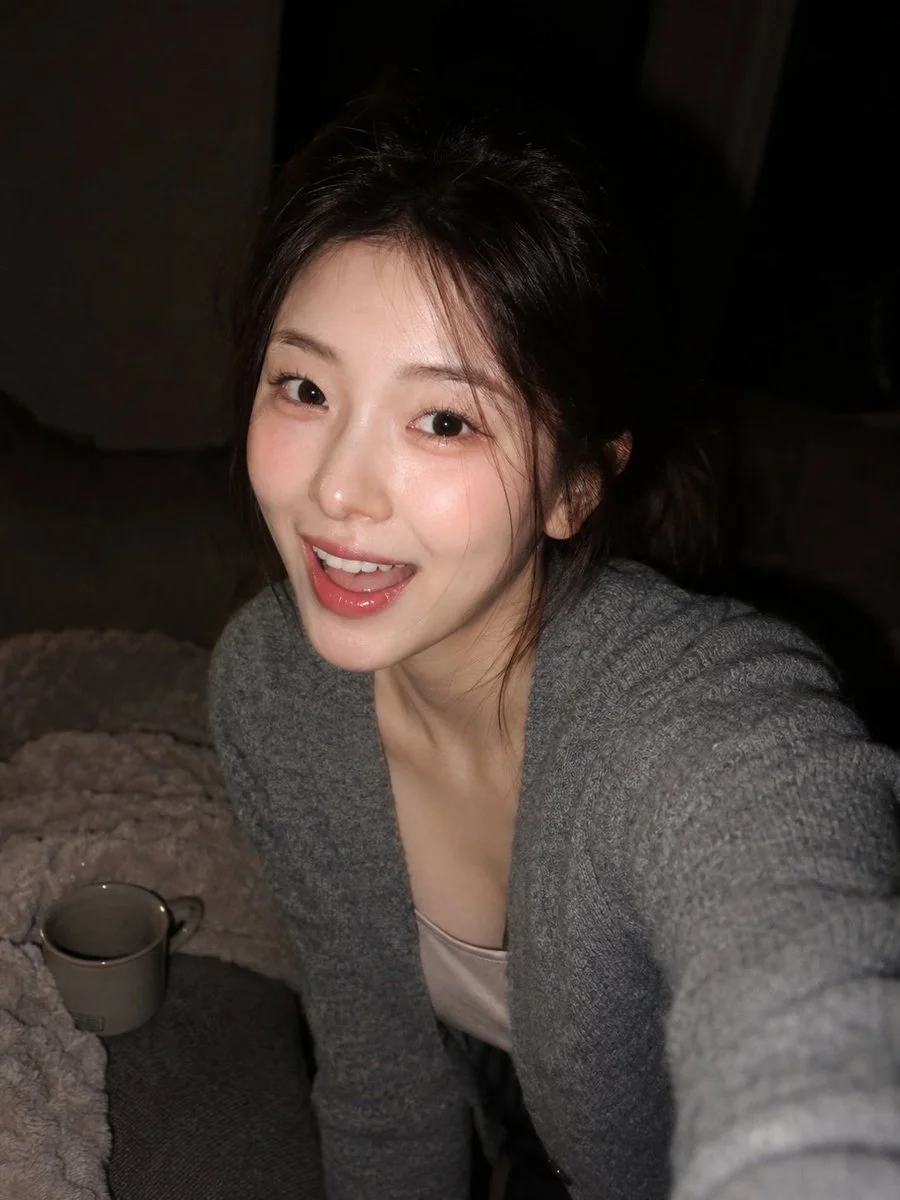 A young Korean woman laughs in a cozy dark room with flash