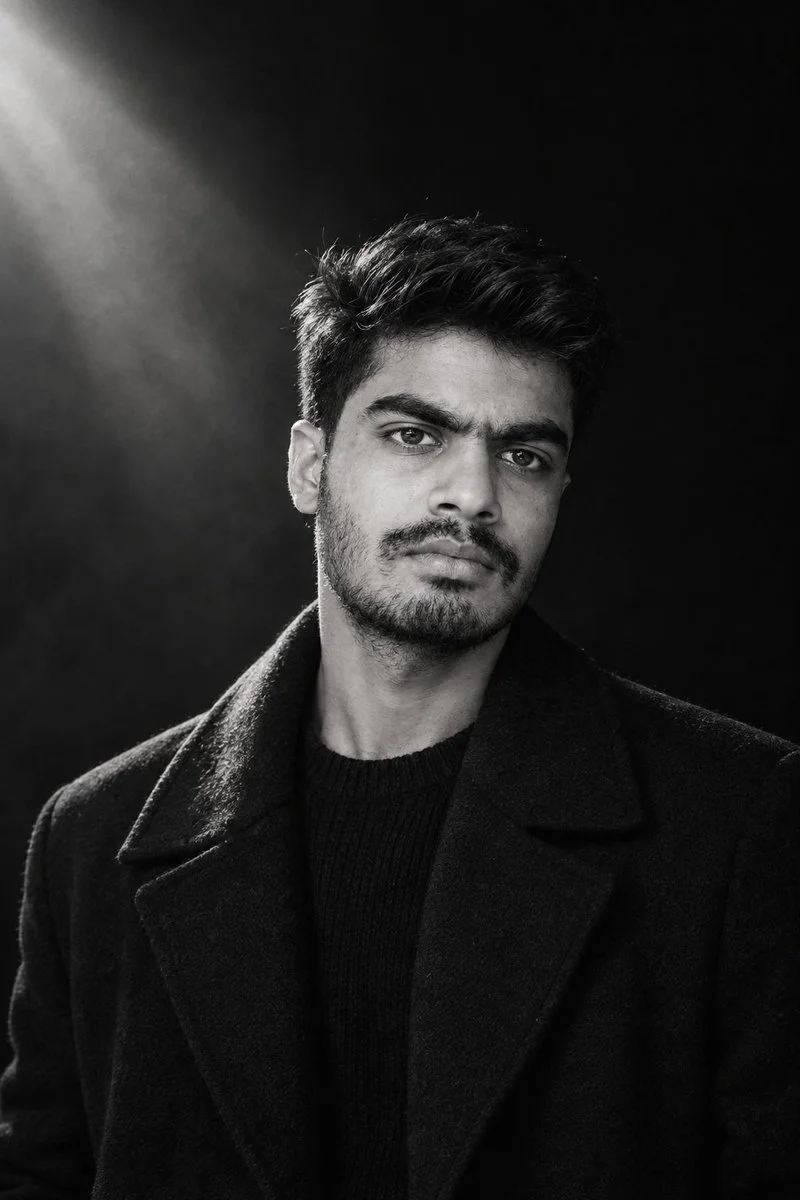A young man emerges from darkness in striking black-and-white portrait