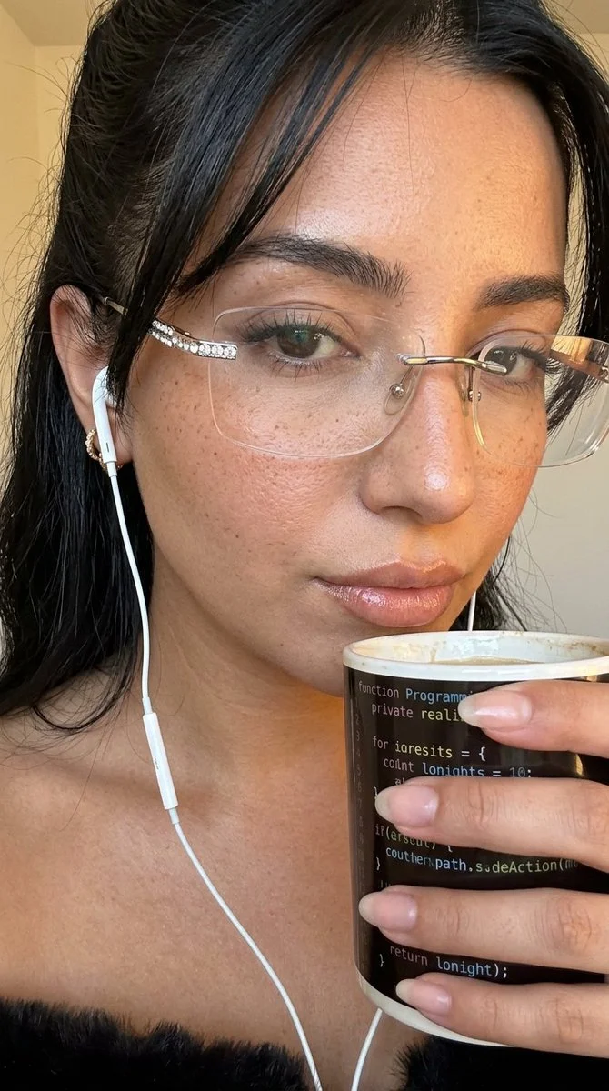 A young woman in rimless glasses holds a glowing code mug