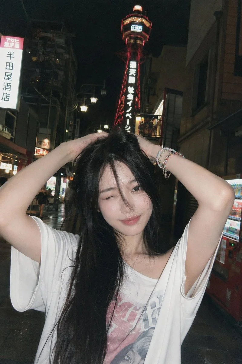 A young woman winks playfully under neon lights in Osaka at night