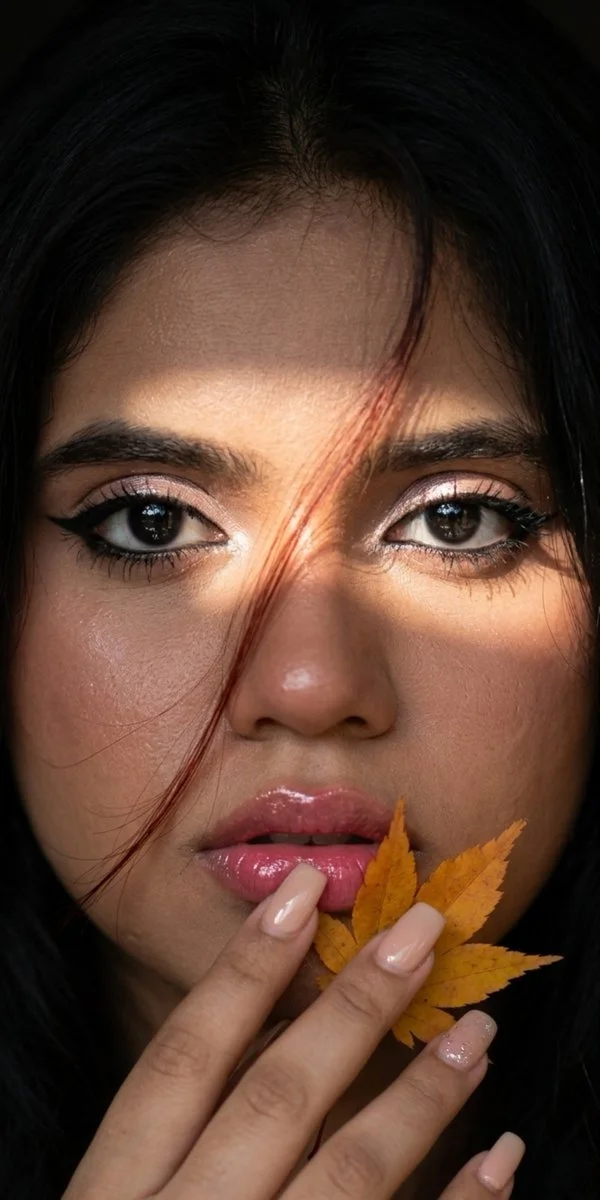 Autumn's golden leaf rests gently on her glossy lips