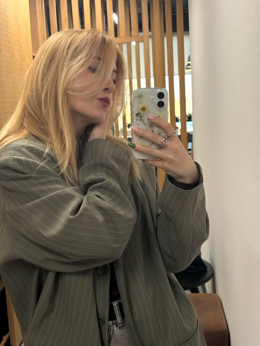 Blonde woman in oversized blazer poses with floral phone case