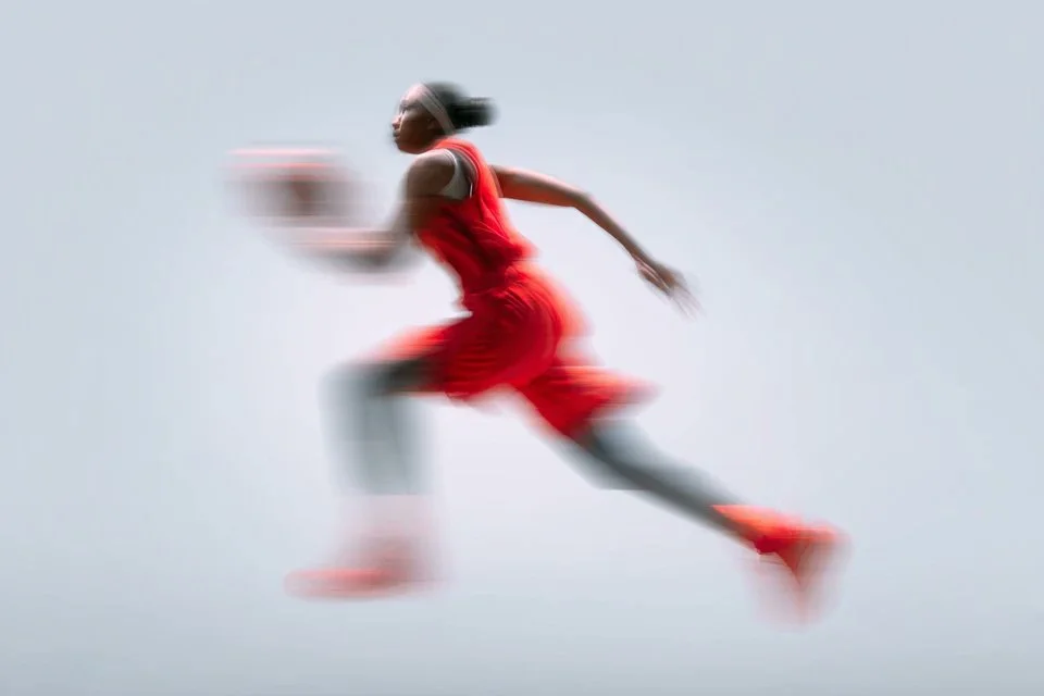 Blurred sprinter in neon orange kit races through neutral backdrop