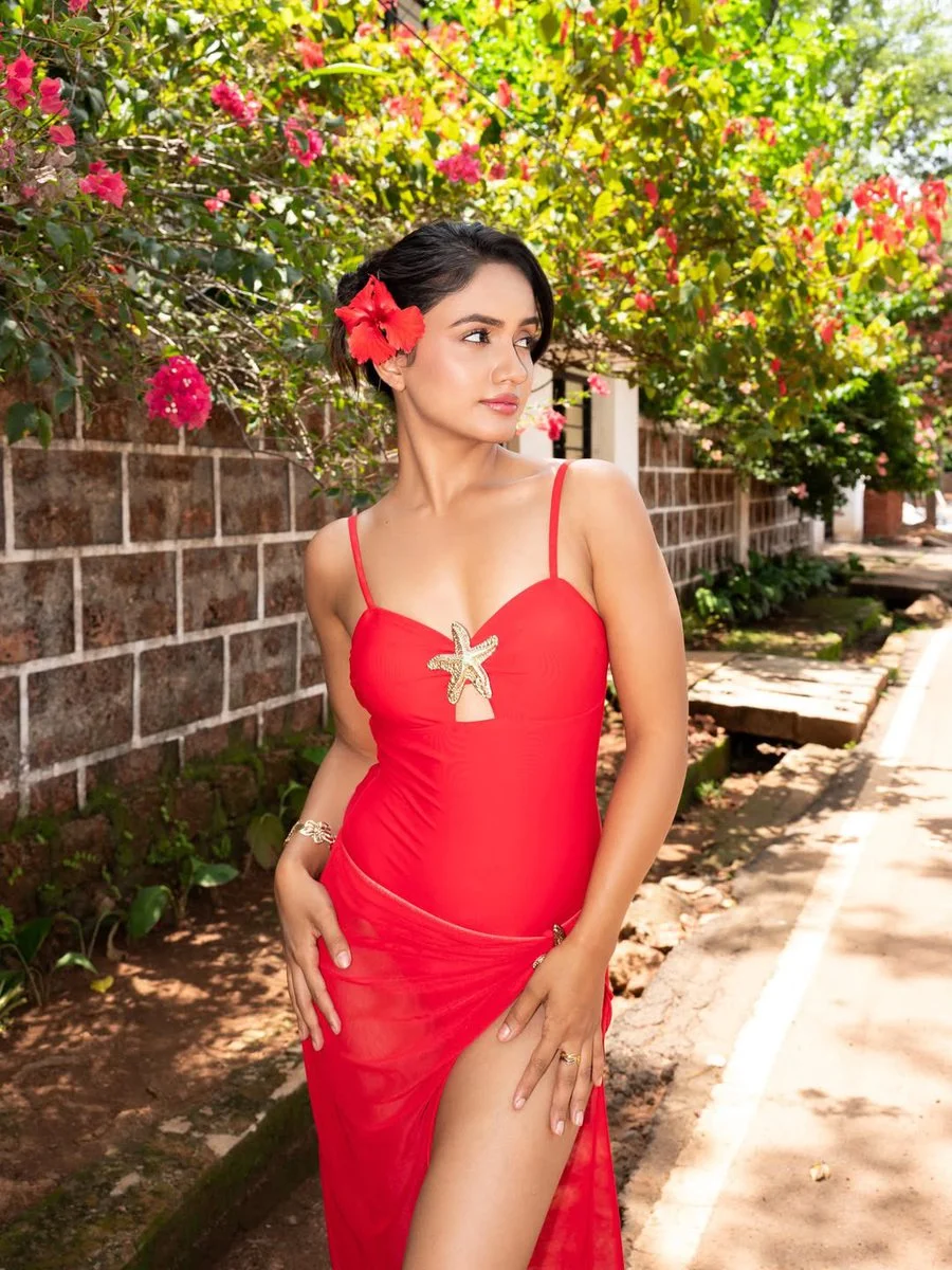 Confident gaze of a woman in red dress amidst vibrant bougainvillea blooms