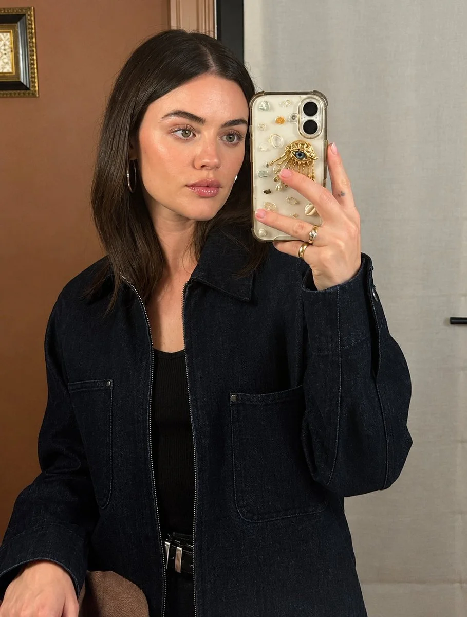 Confident woman captures mirror selfie with gold-accented smartphone