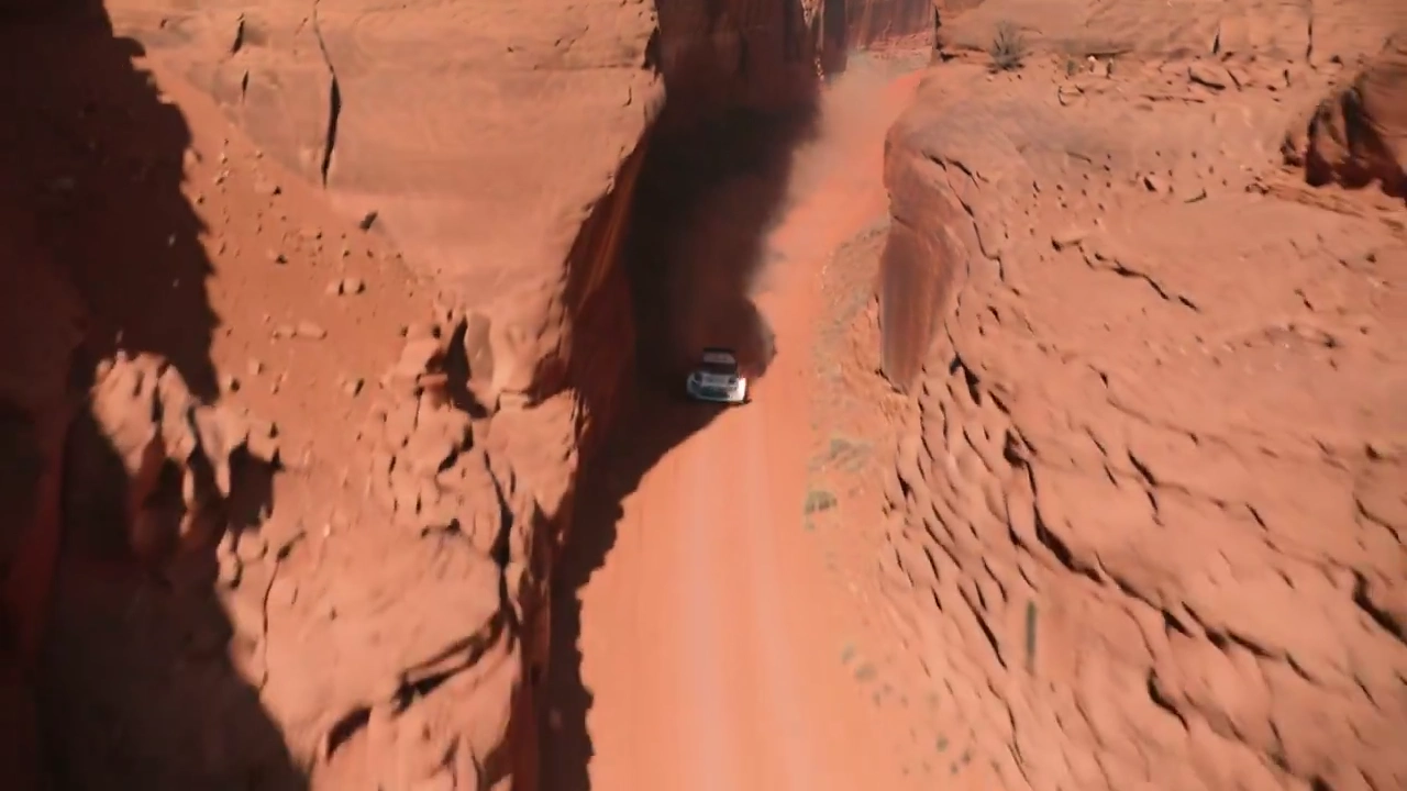 Intense Rally Racing Amidst Towering Desert Cliffs and Dust
