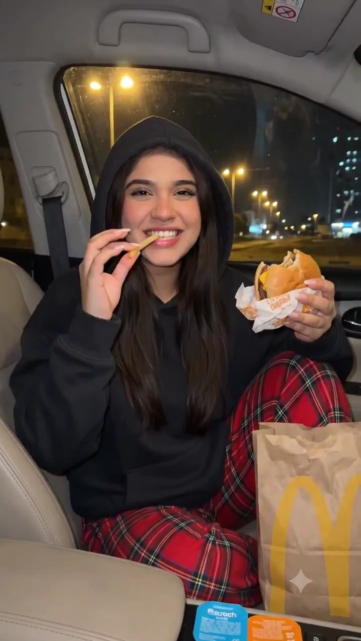 Late-Night Cravings Captured: Hooded Passenger with a Cheeseburger