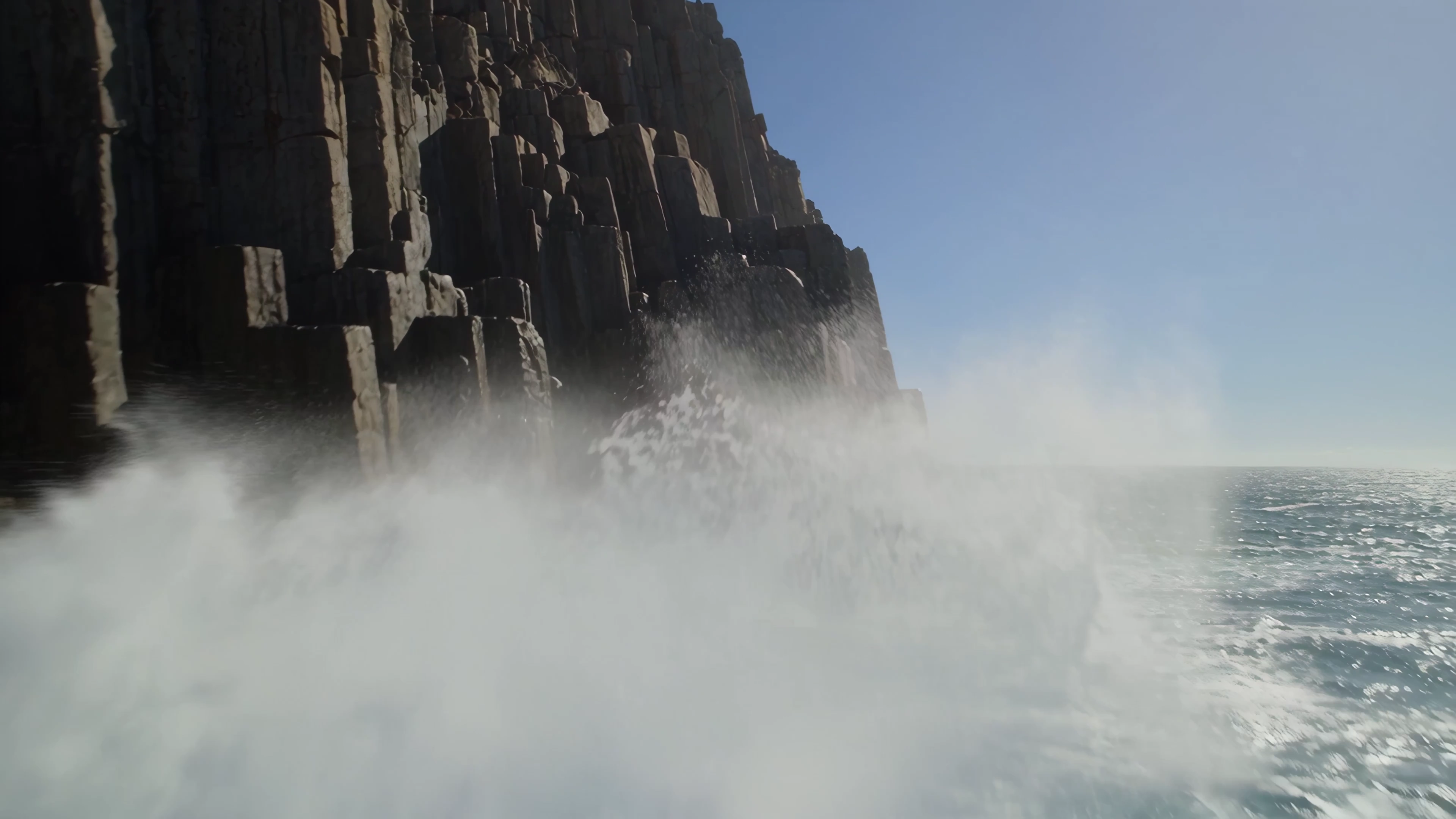 Sunlit Ascent Reveals Solitary Figure Perched Above Roaring Ocean Swells