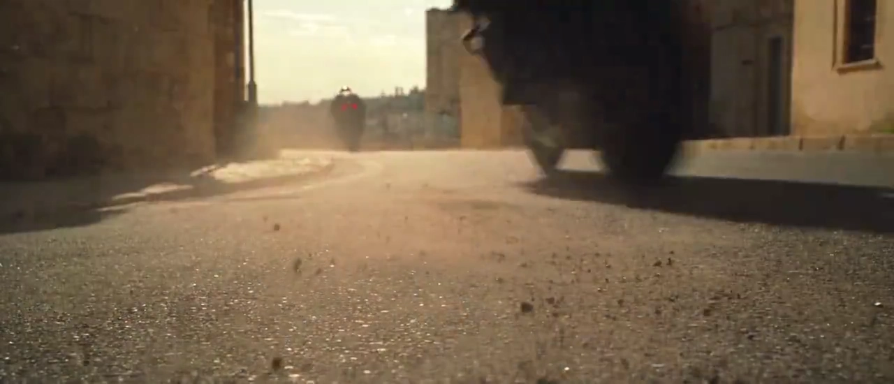 Dark-Haired Woman Grips Superbike Handlebars While Urban Chaos Erupts