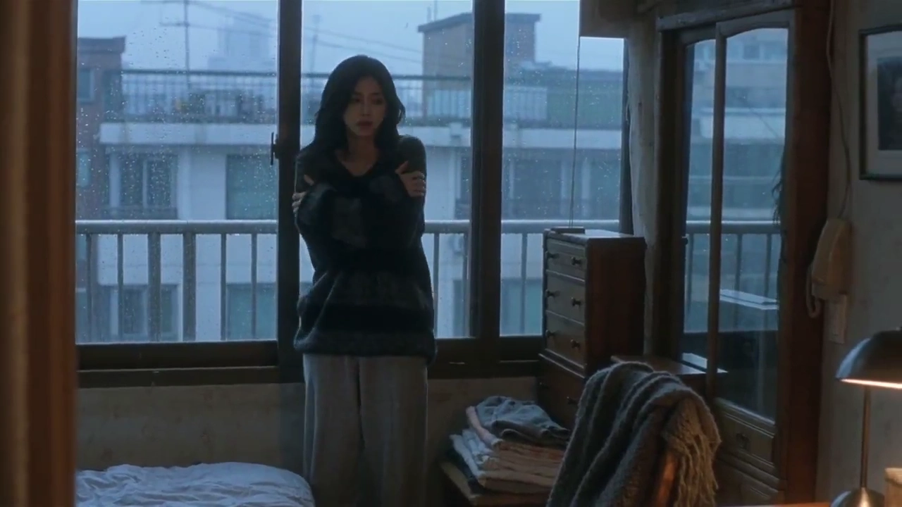 Seoul Woman Shivers by Rainy Window Before Wrapping Soft Shawl