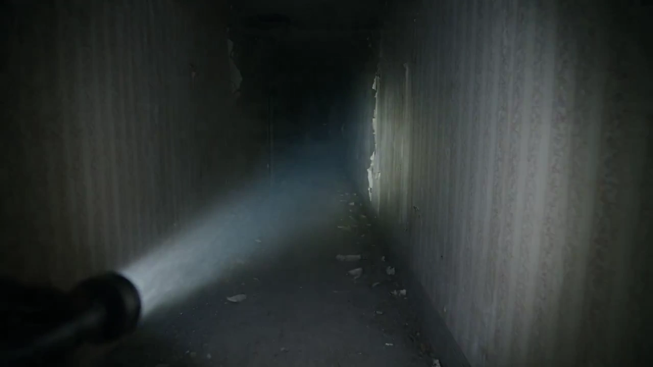 Footsteps echo as a flashlight beam cuts through abandoned darkness