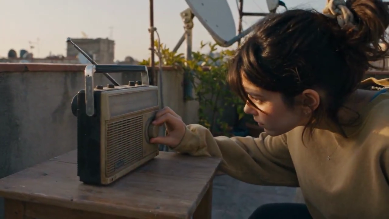 Curly-Haired Woman Tunes Dusty Radio While Laundry Dances in Breeze