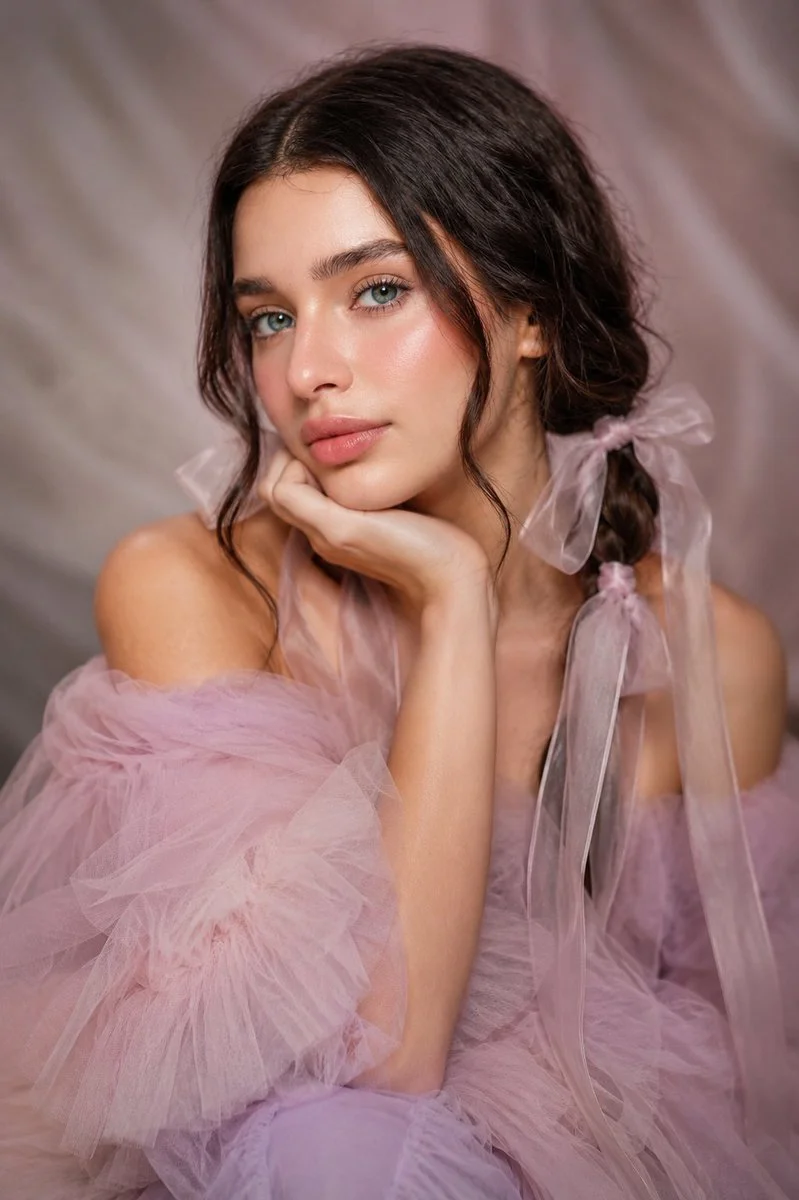 Dark-haired beauty in off-shoulder tulle gown looks at camera