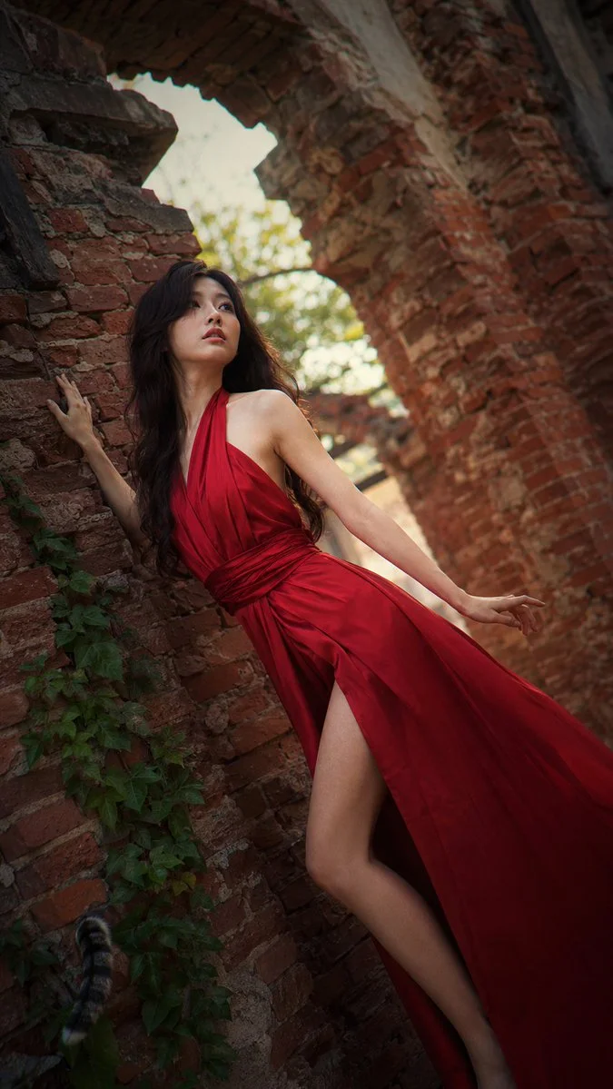 Dreamy fashion portrait with flowing hair and hand pressed against rough brick
