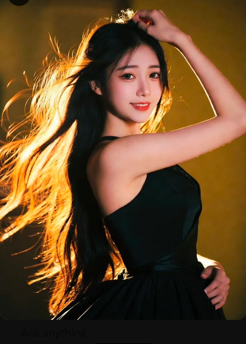 East Asian woman poses in wind with golden backlight on hair