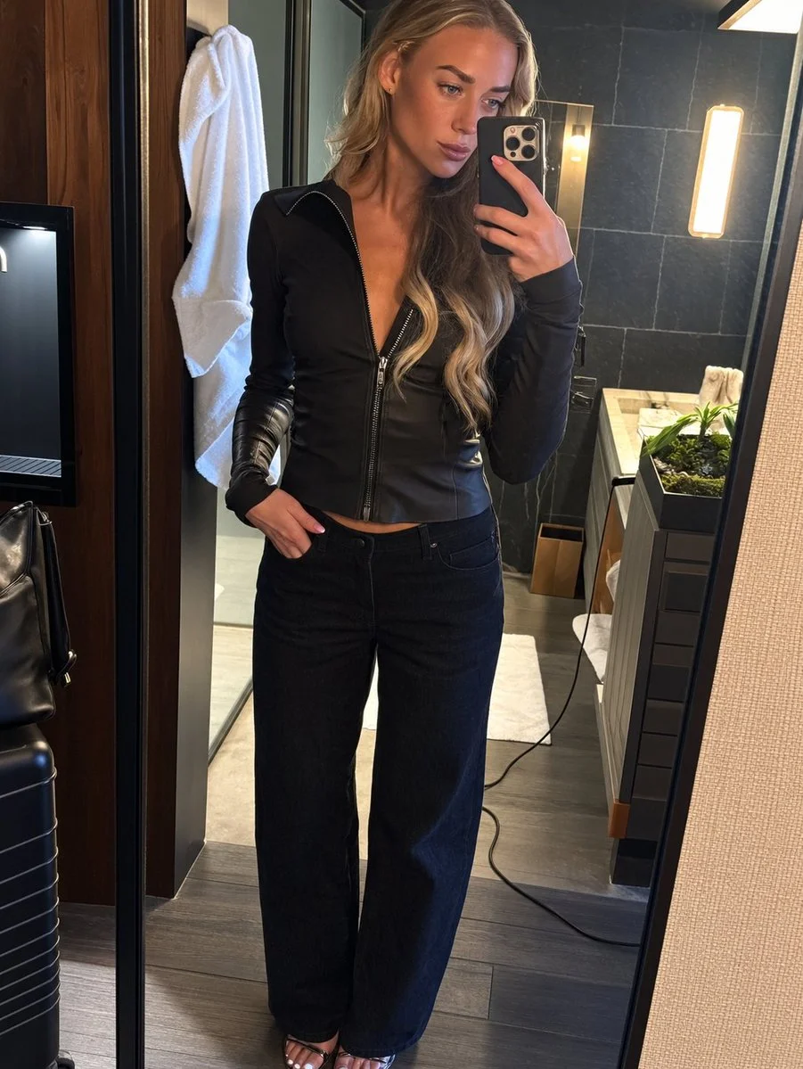 Elegant woman captures casual selfie in modern hotel bathroom with marble walls
