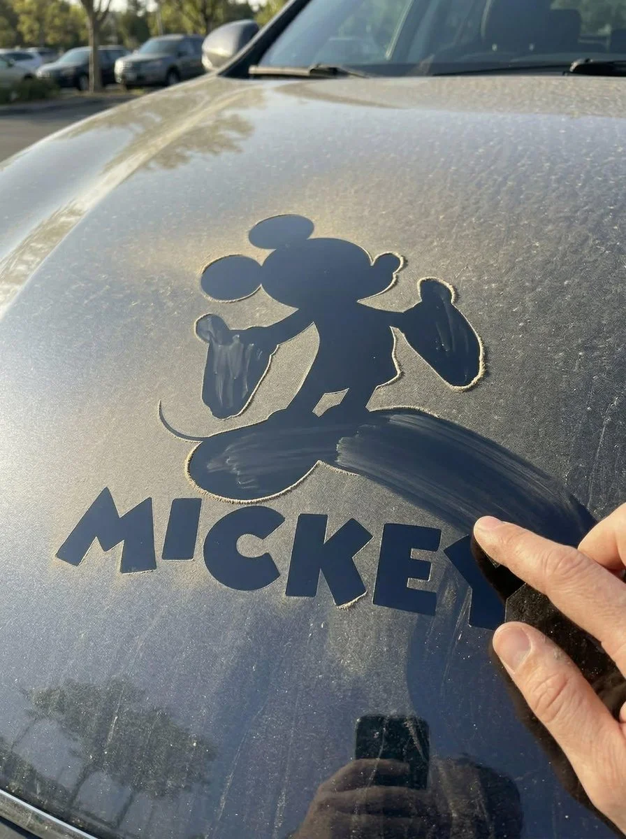 Finger-Traced Logo on Dusty Car Hood