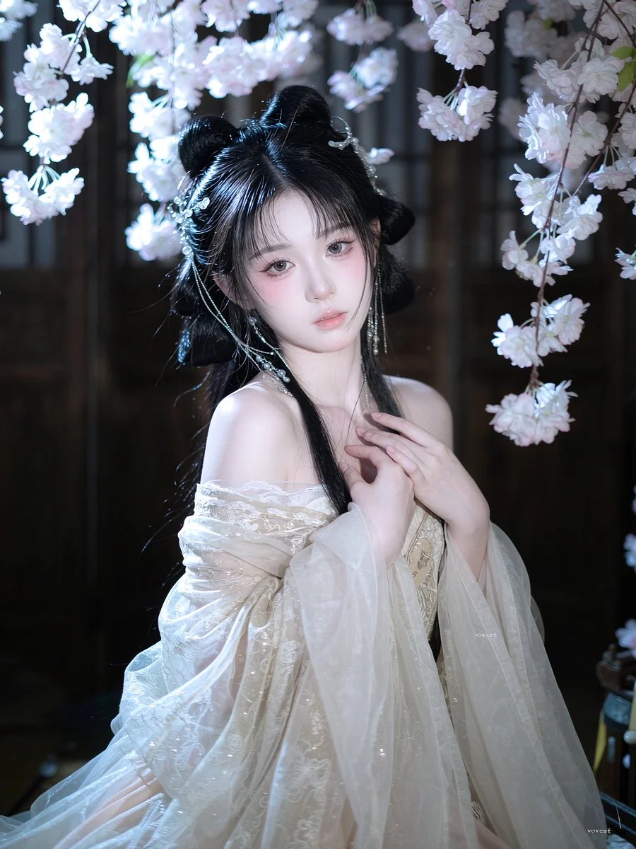 Fragile beauty in ancient gown framed by falling white flowers