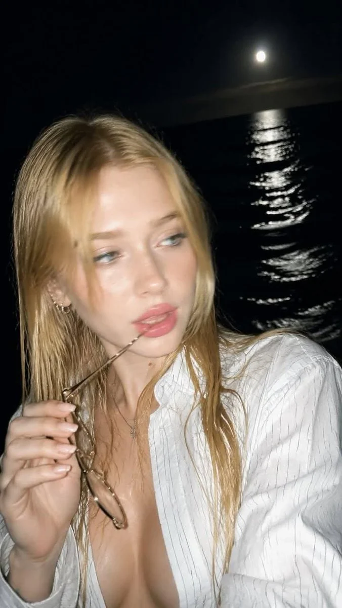 Girl bites glasses as moonlight gleams on dark sea