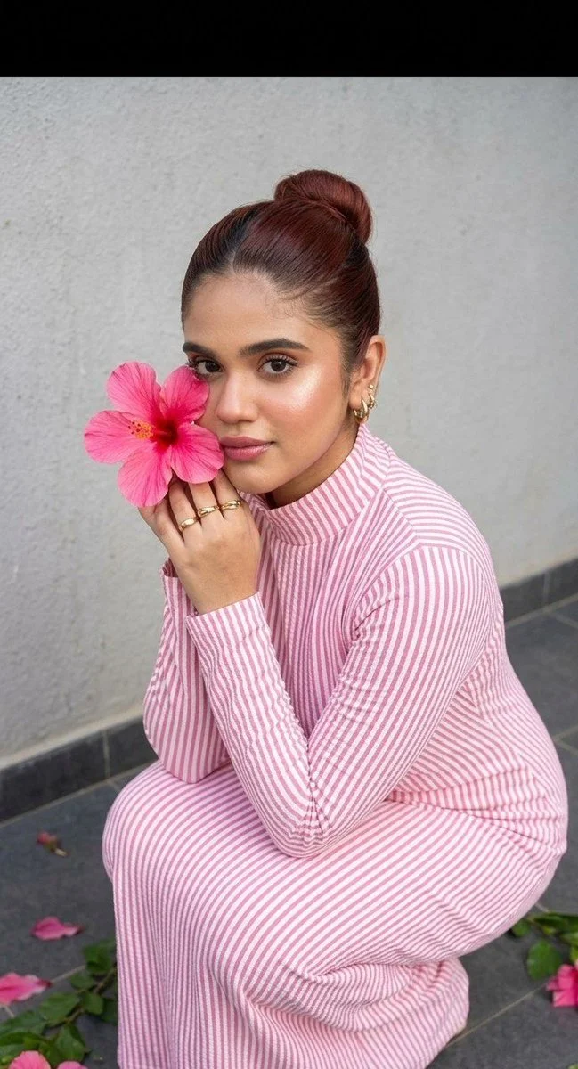 Gold rings and a pink hibiscus adorn a woman in a sunny editorial.