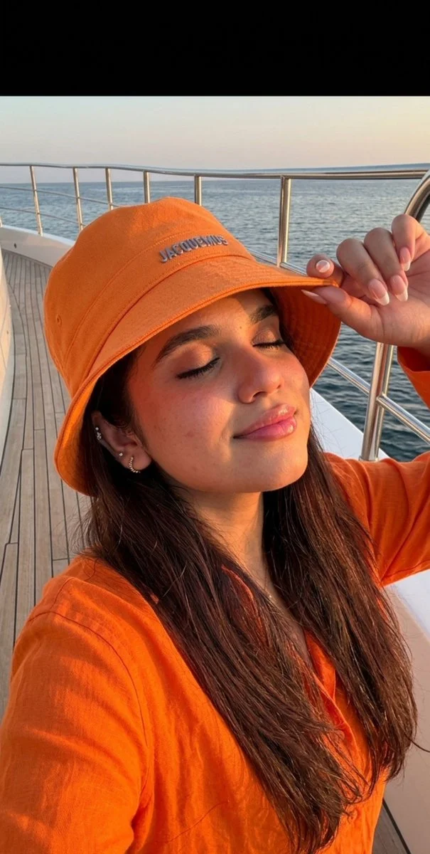Golden hour selfie captures relaxed joy in orange hat