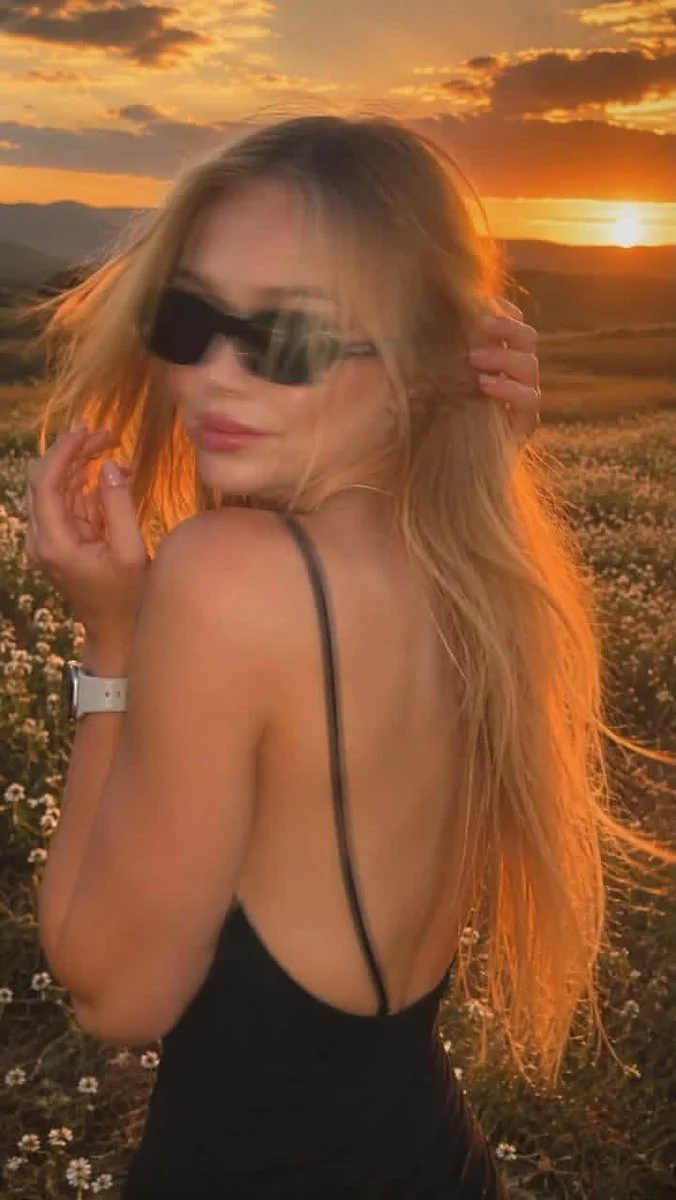Golden sunset catches her turning glance, motion blurring the frame