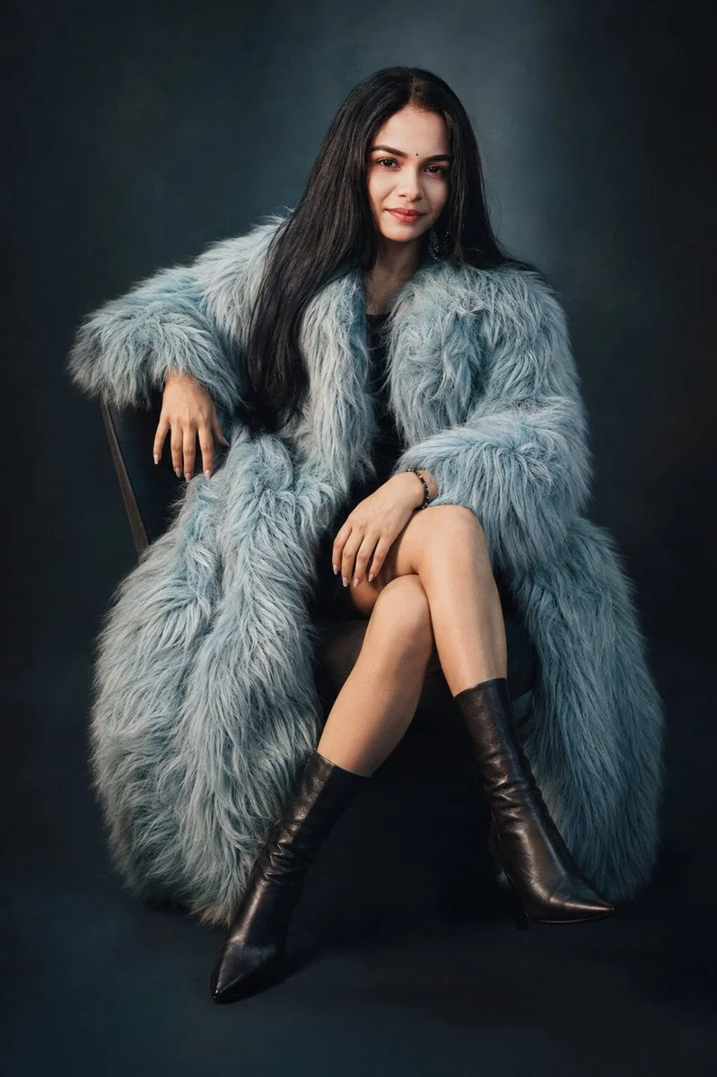 Icy blue fur coat frames confident woman's intense gaze in studio