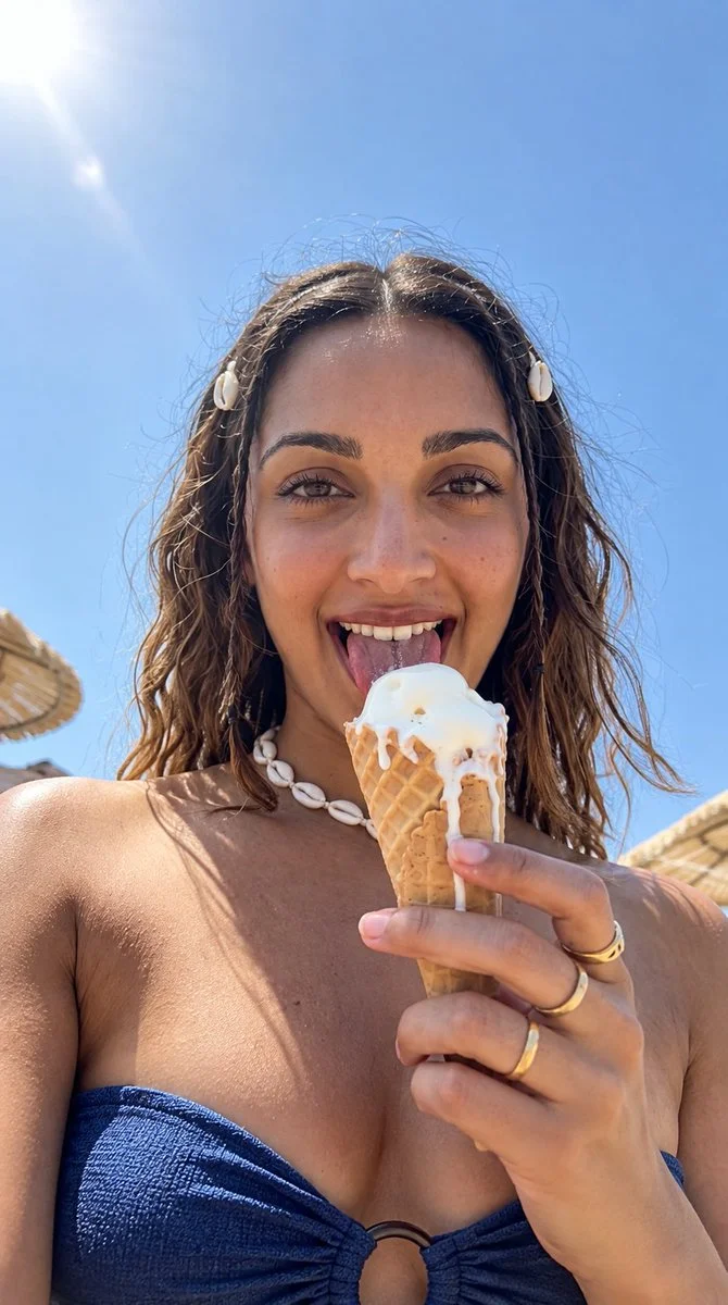Joyful woman licks melting vanilla cone on sunny beach