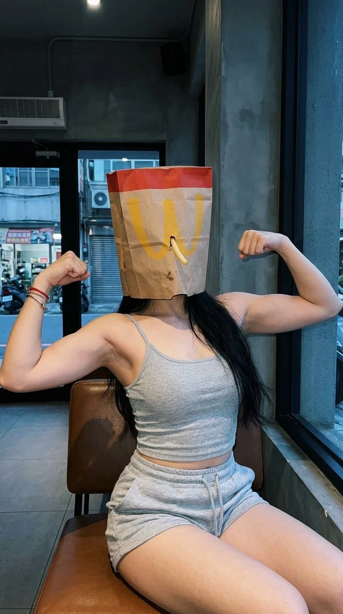 Masked Strength: Woman Flexes Muscles with Playful Paper Bag Cover