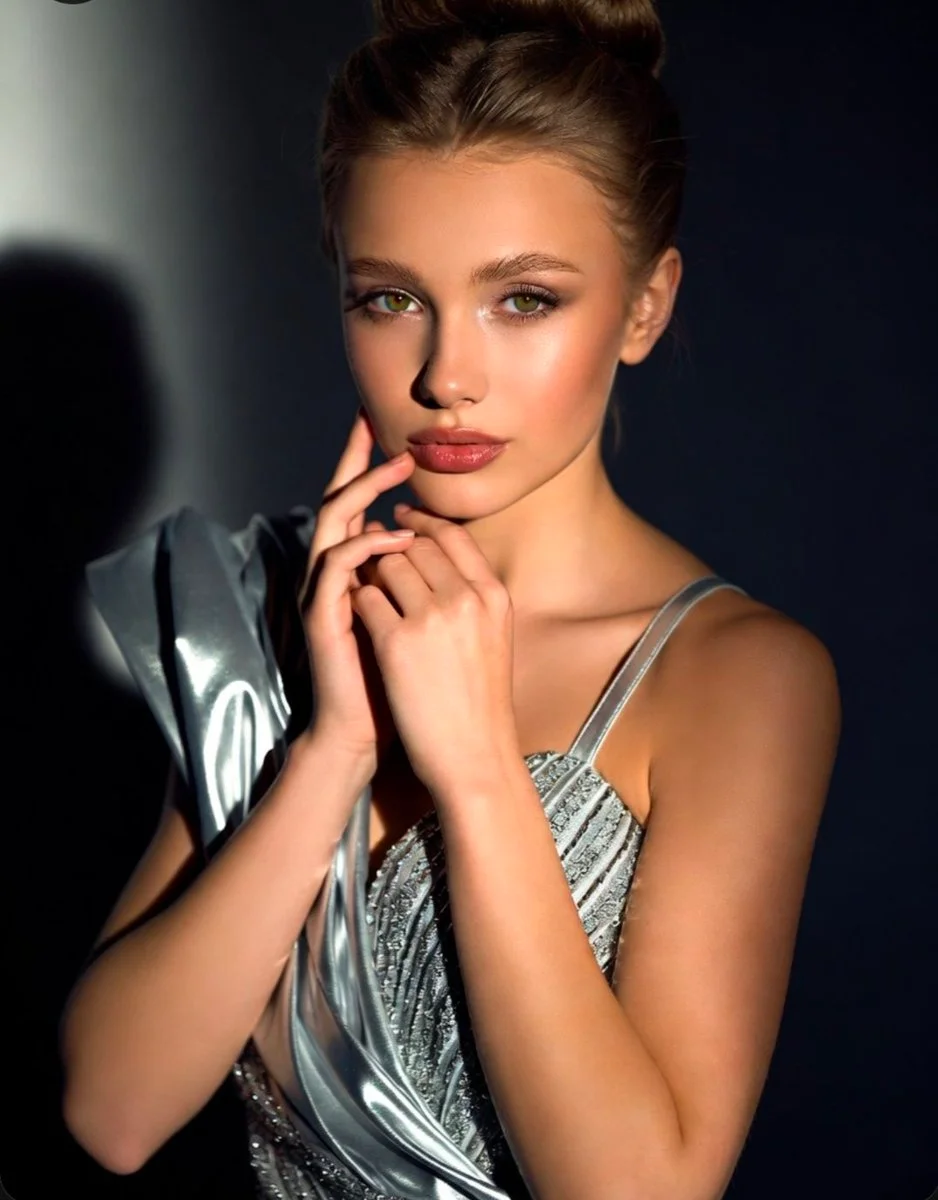 Metallic silver dress drapes dramatically as soft smoky eyes captivate.