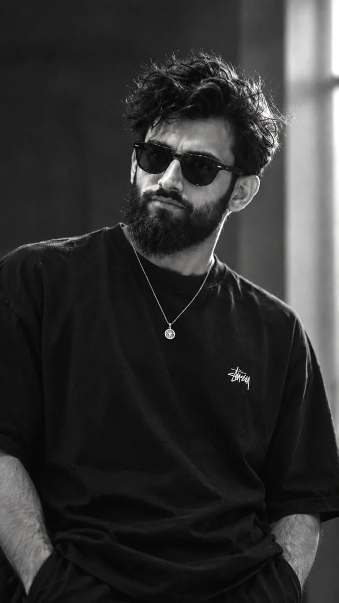 Monochrome portrait captures brooding man with thick beard indoors