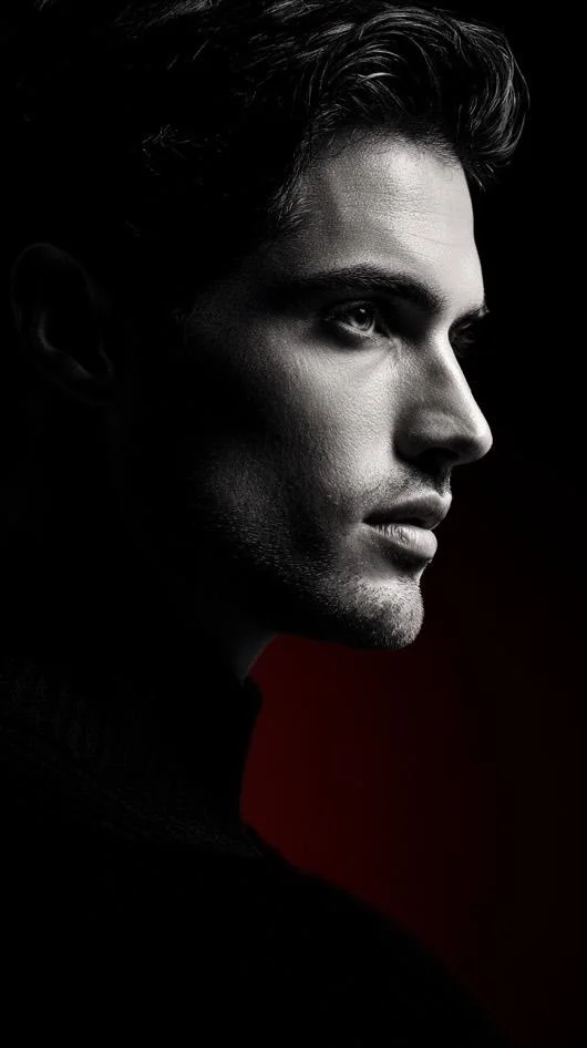 Monochrome studio portrait reveals sharp facial contours and shadows