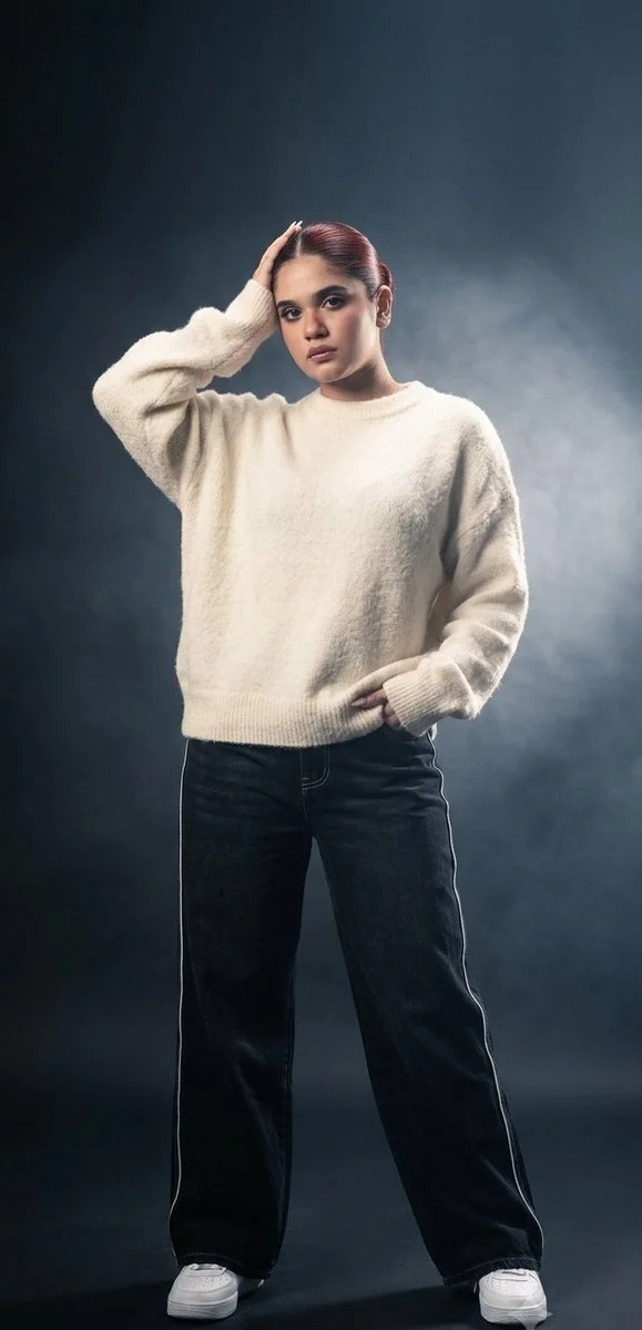 Oversized cream sweater meets relaxed high-fashion stance in studio