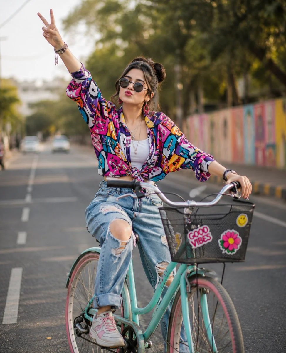 Playful cyclist in double buns flashes peace sign against colorful mural